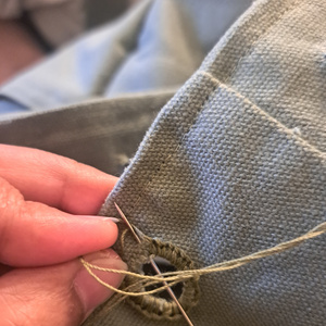 A close-up of an eyelet being hand-stitched.