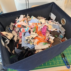 A blue basket containing shreds of fabric.